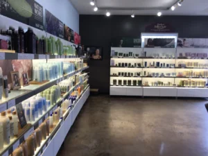 IMG_2540 Shelves in a well-lit store display various hair care and beauty products in bottles and tubes along the walls, with promotional posters above the shelves.